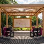 Outdoor Classroom Design - Professional 16:9 hero banner. Ultra high resolution. An inspiring architectural detail of a modern, well-integrated outdoor classroom within the grounds of a prestigious UK primary school. The scene features a durable timber canopy extending over a functional learning zone, with children's colourful drawings subtly visible on an outdoor whiteboard and robust, BS EN 1729 compliant recycled plastic furniture arranged neatly. Sunlight filters through the canopy, creating dappled shadows. A soft, inviting #737373 glow accentuates the learning area, with elements of #E2087E and #000000 subtly defining pathways or furniture details. Style: Architectural photography with a warm, inviting atmosphere. Avoid: Groups of people, generic playgrounds, cold blue tones.
