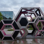 Outdoor Pub Furniture - Professional 16:9 hero banner. Ultra high resolution. A sophisticated, abstract geometric pattern representing strategic planning and robust construction, with interlocking shapes symbolising durability and modularity. The design incorporates subtle elements of football (e.g., hexagonal patterns) without being overt, set against a backdrop suggesting a modern UK commercial outdoor space, perhaps a well-maintained pub garden or school courtyard. Key elements are highlighted with a #737373 accent glow, while #E2087E and #000000 tones provide structure and depth. The overall mood is authoritative and intelligent, reflecting expertise in commercial furniture solutions. Style: Architectural photography with a conceptual, clean aesthetic. Avoid: Groups of people, generic pub scenes, overly literal depictions of football, cold blue tones.