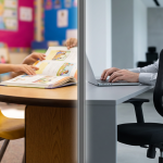 School Furniture vs Office Furniture - Professional 16:9 hero banner. Ultra high resolution. A split image, visually representing the stark contrast between robust, child-centric school furniture and standard adult office furniture. On the left, a sturdy, bright yellow school chair and a small, rounded-edge table, with children's hands (out of focus) interacting with a textbook. On the right, a sleek, ergonomic office chair and a minimalist desk, with an adult's hand (out of focus) typing on a laptop. A subtle, glowing vertical line in #737373 divides the two scenes, symbolising the clear distinction and the critical choice. The background on the left is a vibrant, active classroom setting with elements of #E2087E, while the right features a calm, professional office environment with touches of #000000. Style: Editorial photography with a focus on contrasting elements and clear visual storytelling.
