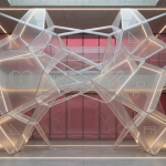 School Procurement - Professional 16:9 hero banner. Ultra high resolution. A meticulously organised, abstract geometric pattern representing strategic planning and compliance in school procurement. The pattern is composed of interlocking, translucent educational symbols like an open book, a desk, and a ruler, subtly integrated into a complex framework. The scene is illuminated by an accent glow of #737373, highlighting the structure and precision. A deeper #E2087E provides a subtle background hue, suggesting the educational environment. The overall mood is authoritative and structured, reflecting the reliable service of Cost Cutters UK. Style: Fine art architectural photography. Avoid: Groups around holographic tables, generic tech aesthetics, text overlays, cold blue tones, stock photo clichés.