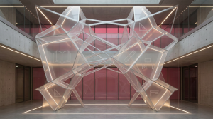 School Procurement - Professional 16:9 hero banner. Ultra high resolution. A meticulously organised, abstract geometric pattern representing strategic planning and compliance in school procurement. The pattern is composed of interlocking, translucent educational symbols like an open book, a desk, and a ruler, subtly integrated into a complex framework. The scene is illuminated by an accent glow of #737373, highlighting the structure and precision. A deeper #E2087E provides a subtle background hue, suggesting the educational environment. The overall mood is authoritative and structured, reflecting the reliable service of Cost Cutters UK. Style: Fine art architectural photography. Avoid: Groups around holographic tables, generic tech aesthetics, text overlays, cold blue tones, stock photo clichés.