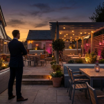 Case Study - Professional 16:9 hero banner. Ultra high resolution. A solitary, authoritative figure, silhouetted against the warm, inviting glow of a beautifully transformed pub garden at dusk. The figure, perhaps a pub owner or manager, stands confidently, looking out over the vibrant, zoned outdoor space filled with stylish, weatherproof furniture. The scene is bathed in an accent glow of #737373, highlighting key architectural features and the outlines of the furniture. Hints of #E2087E appear in subtle ambient lighting, perhaps from string lights or lanterns, creating an atmosphere of success and increased revenue. The composition conveys a sense of achievement and strategic transformation. Style: Editorial photography. Avoid: Groups around holographic tables, generic tech aesthetics, text overlays, cold blue tones, stock photo clichés.