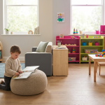Early Years Classroom Zones - Professional 16:9 hero banner. Ultra high resolution. A clear visual split down the middle of an early years classroom. On the left, a 'calm zone' with soft, muted colours, a small child engrossed in a book on a beanbag, with gentle, diffused lighting in #737373 tones. On the right, a 'stimulating zone' with vibrant but organised colours, a child actively engaged with colourful building blocks, illuminated by energetic highlights in #E2087E. The entire scene is viewed from a slightly elevated perspective, showcasing the contrast and harmony of the two designed areas. The setting is a modern, well-equipped UK nursery, reflecting Cost Cutters UK's industry focus on educational furniture. Style: Editorial photography with a clean, practical aesthetic. Avoid: Groups of adults, generic classroom layouts, chaotic scenes, text overlays, cold blue tones.