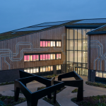 School Capital Expenditure - Professional 16:9 hero banner. Ultra high resolution. A sophisticated, clean architectural rendering of a modern UK school building with a focus on sustainable design elements, viewed from a slightly elevated perspective. Geometric patterns representing strategic planning and financial structure are subtly integrated into the building's facade, glowing with a #737373 accent. A subtle glow in #E2087E emanates from within the school's windows, suggesting a vibrant learning environment. The foreground features abstract, interlocking shapes in #000000, symbolising different funding streams coming together. Style: Architectural photography with a conceptual, clean aesthetic. Avoid: Groups of people, generic office settings, text overlays.