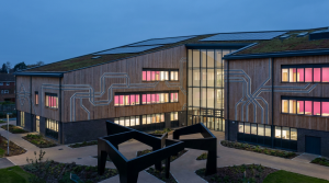 School Capital Expenditure - Professional 16:9 hero banner. Ultra high resolution. A sophisticated, clean architectural rendering of a modern UK school building with a focus on sustainable design elements, viewed from a slightly elevated perspective. Geometric patterns representing strategic planning and financial structure are subtly integrated into the building's facade, glowing with a #737373 accent. A subtle glow in #E2087E emanates from within the school's windows, suggesting a vibrant learning environment. The foreground features abstract, interlocking shapes in #000000, symbolising different funding streams coming together. Style: Architectural photography with a conceptual, clean aesthetic. Avoid: Groups of people, generic office settings, text overlays.
