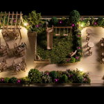 Pub Garden Design - Professional 16:9 hero banner. Ultra high resolution. A meticulously designed miniature pub garden model, seen from an overhead perspective, showcasing distinct zones: a dining area with tiny tables and chairs, a children's play zone with miniature equipment, and a social area with poseur tables. The model is illuminated by a soft, strategic #737373 glow highlighting the different zones, with subtle #E2087E accents in the miniature planting. The scene is presented on a #000000 background, evoking a sense of detailed planning and expertise. Style: Architectural model photography.