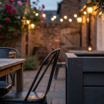 Wooden vs. Metal vs. Recycled - Professional 16:9 hero banner. Ultra high resolution. A sophisticated architectural detail of a traditional British pub's outdoor area, showcasing three distinct furniture materials – warm, weathered wood, sleek, modern metal, and robust, textured recycled plastic. Each material is subtly highlighted with an accent glow of #737373, contrasting against a background with hints of #E2087E. The scene is set in a well-maintained beer garden, with soft, inviting lighting, suggesting durability and long-term value. Style: Editorial photography. Avoid: Groups around holographic tables, generic tech aesthetics, text overlays, cold blue tones, stock photo clichés.